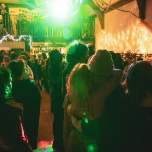 A group of people dance in a function room as a green light flashes from above