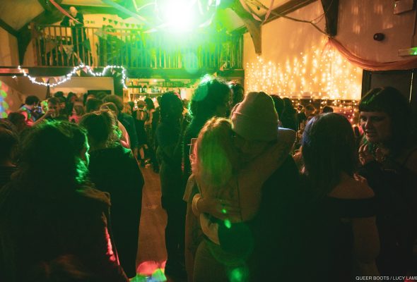 A group of people dance in a function room as a green light flashes from above