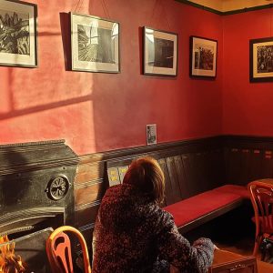 Person looking at an exhibition in the Gregson Cafe Bar sat next to the roaring fire