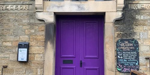Picture of the Gregson Centre's freshly painted door. The door is purple with black door furnishings