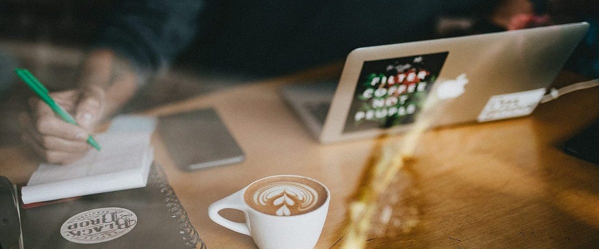 Image of person writing with a coffee